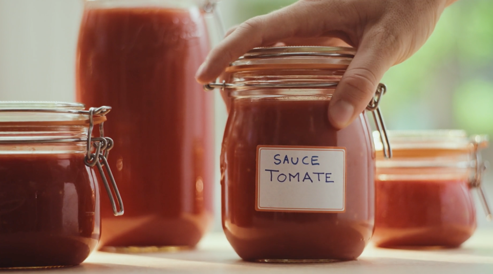 Main tenant un bocal de sauce tomate Le Parfait